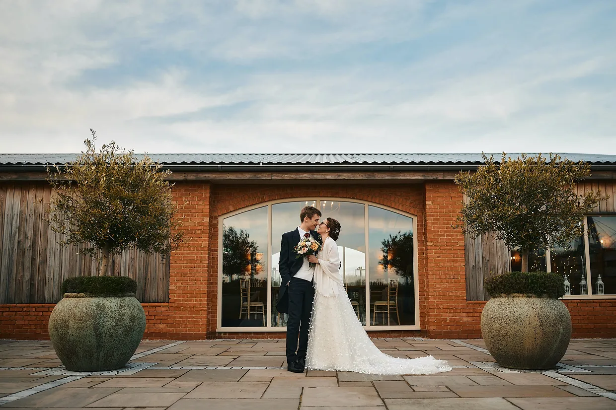 Couple on terrace during reception at barn wedding venue with accommodation in the cotswolds